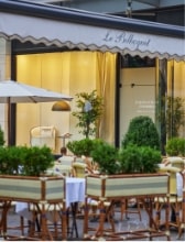 Charming outdoor café with striped chairs, potted plants, and elegant table settings at Le Bilboquet restaurant.